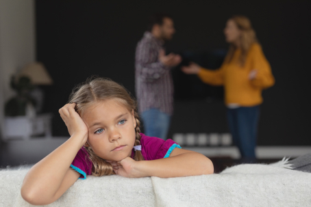 sad child with parents fighting in the background