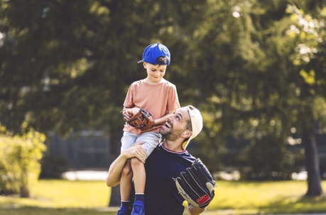 father and son playing baseball in the park